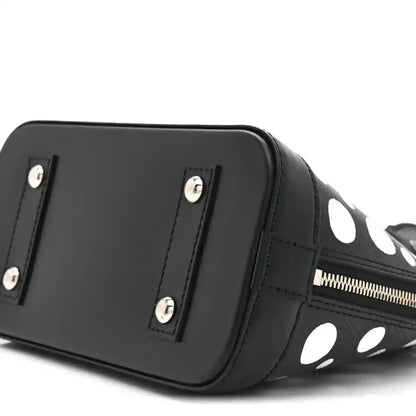 Alma BB bag angled side with smooth black panel, silver studs, and polka-dot trim