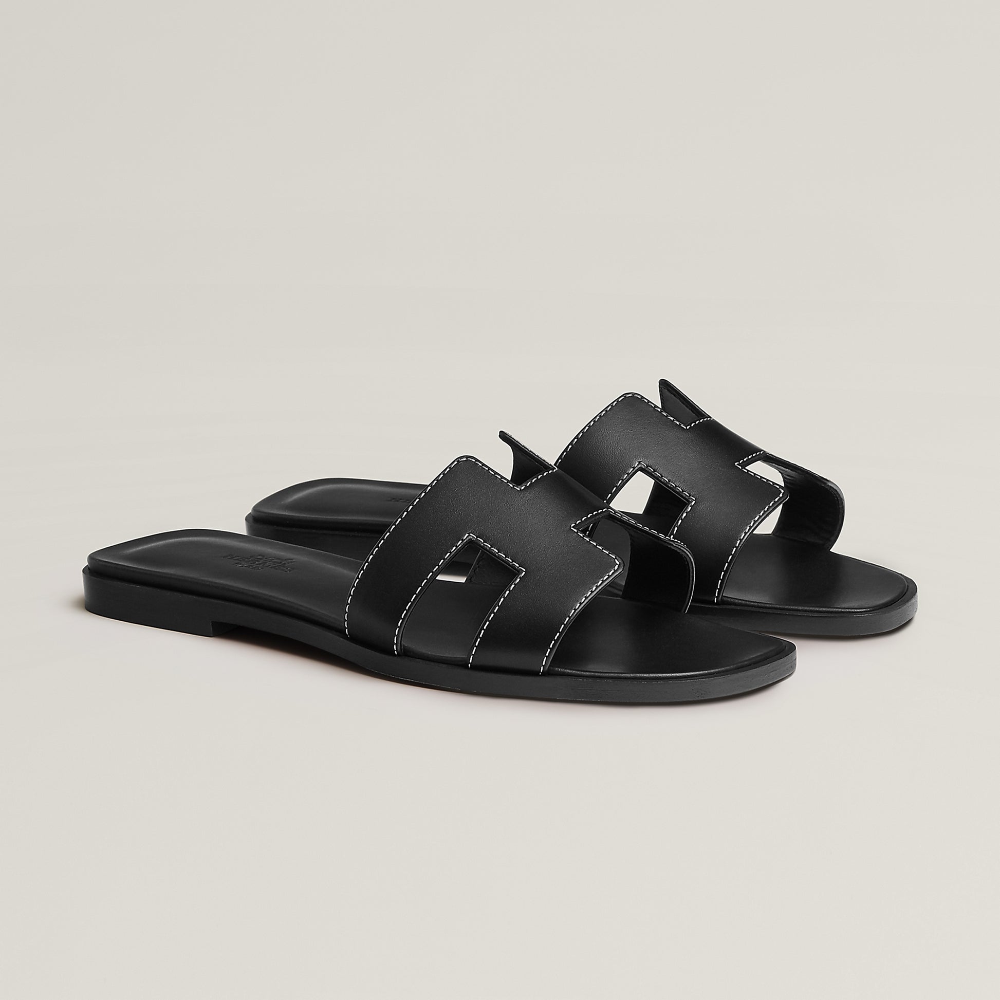 Black leather slide sandal with two wide straps and stitched H-style cutouts
