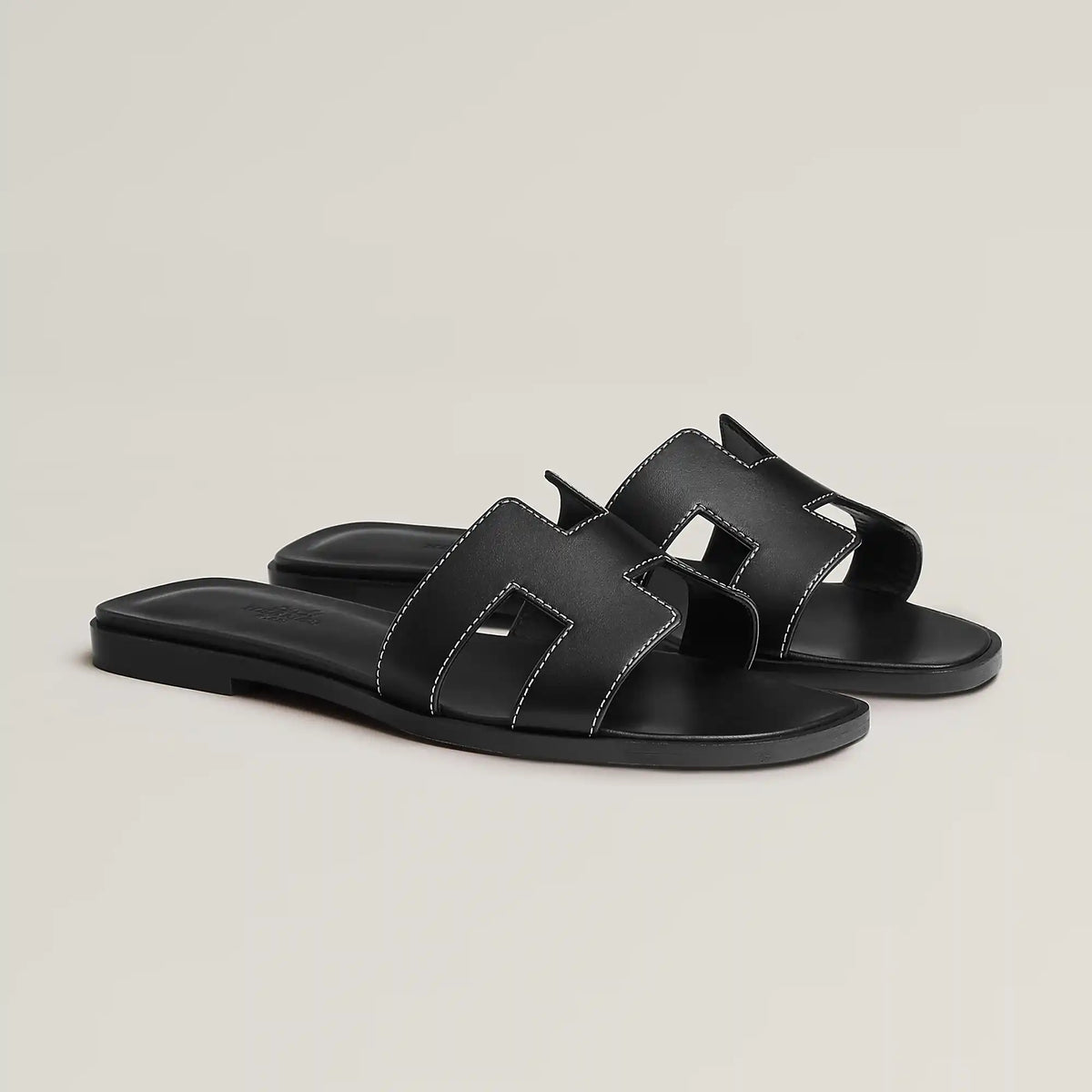 Black leather slide sandal with two wide straps and stitched H-style cutouts