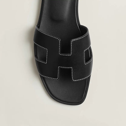 Black leather slide sandal upper close-up with stitched H-style cutouts and open toe