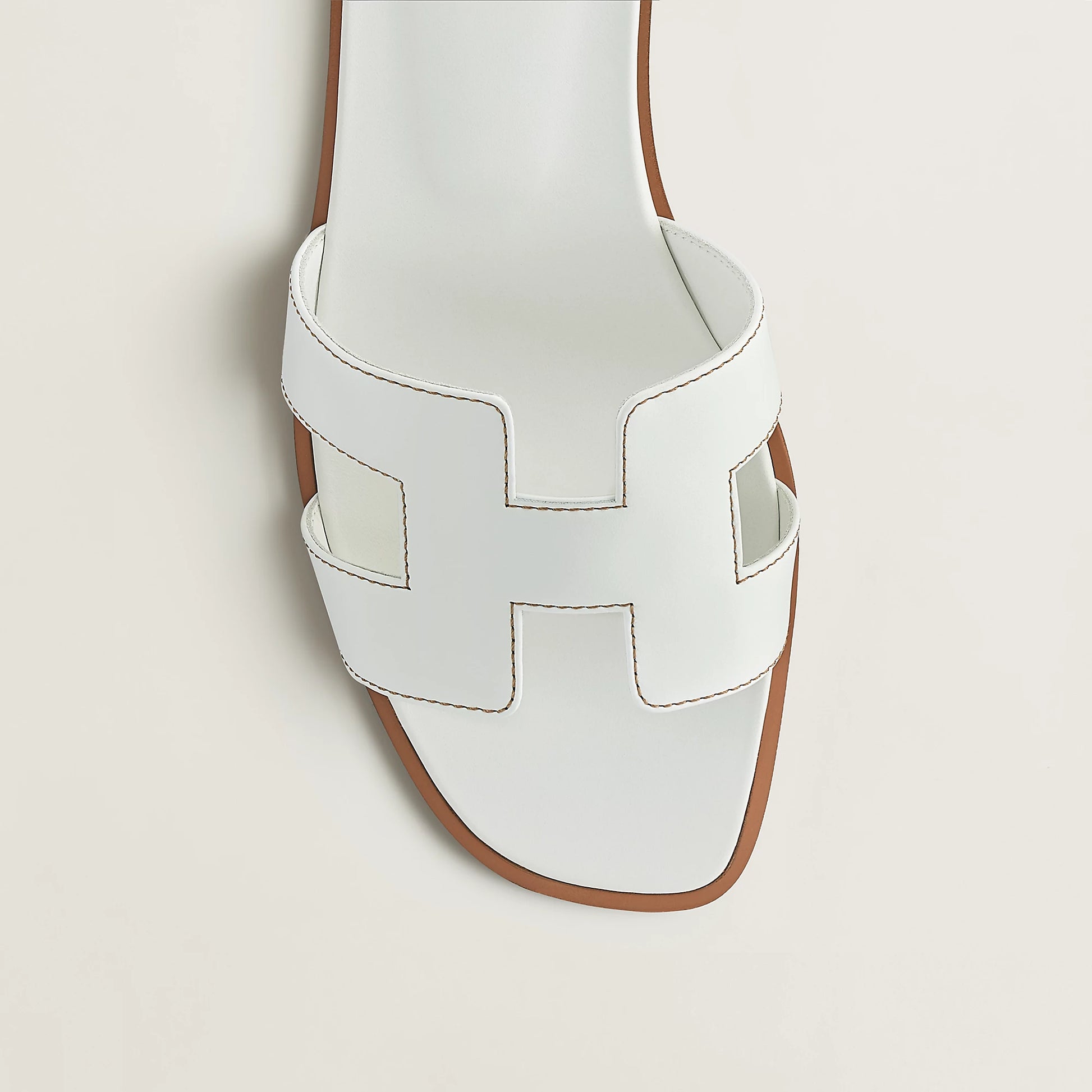 White leather slide sandal upper close-up with stitched H-style cutouts and open toe