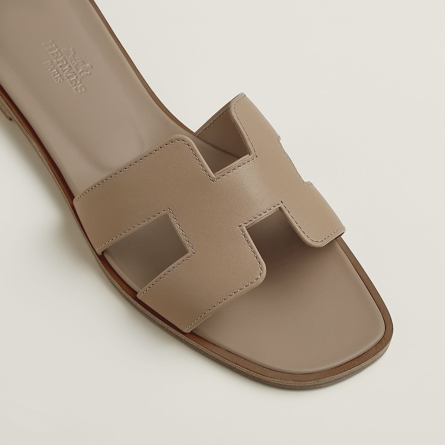 Hermès Oran slide sandal close-up, light beige leather upper with square strap cutouts