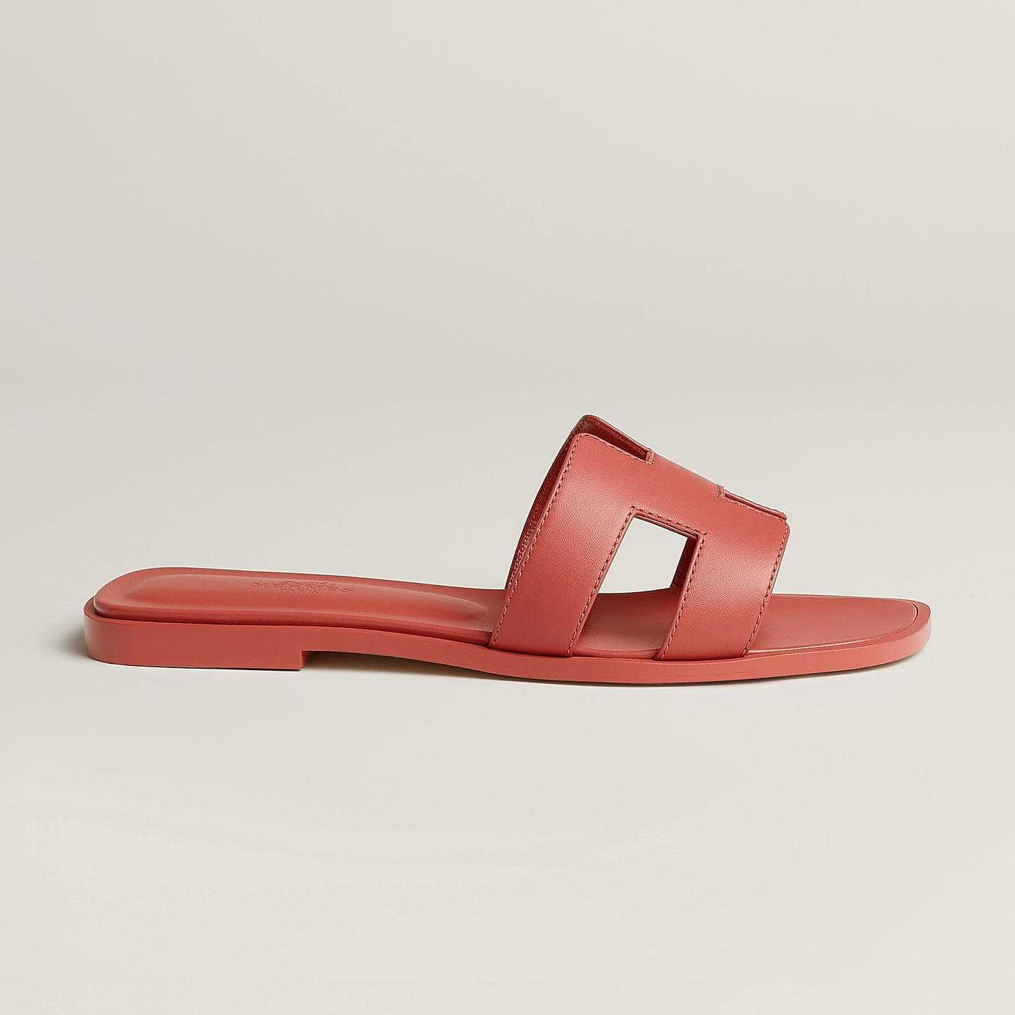 Red leather slide sandal with rectangular cutout straps and flat rubber sole
