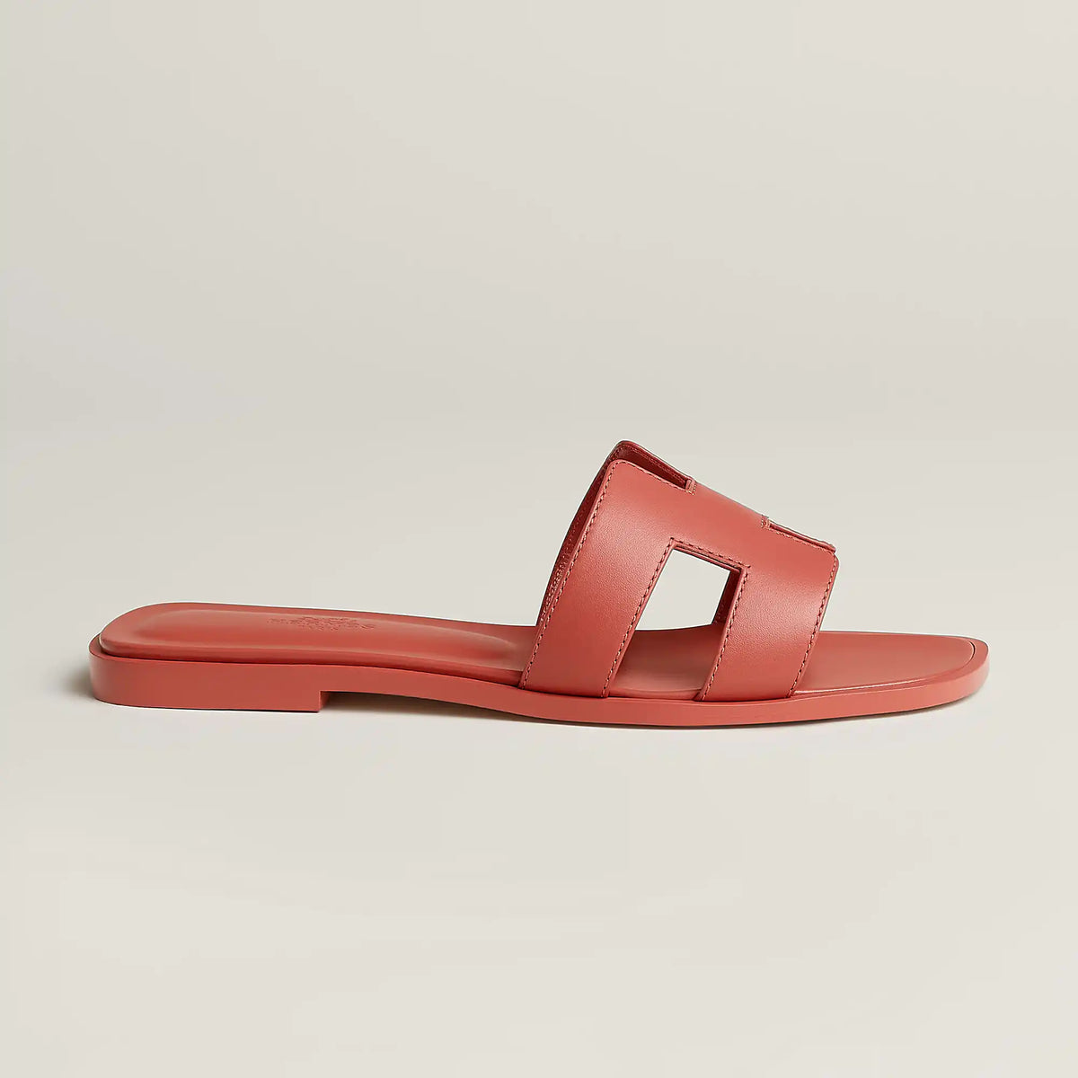 Red leather slide sandal with rectangular cutout straps and flat rubber sole