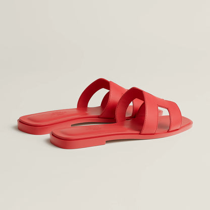 Red leather slide sandals with wide straps and open toe, shown in side view