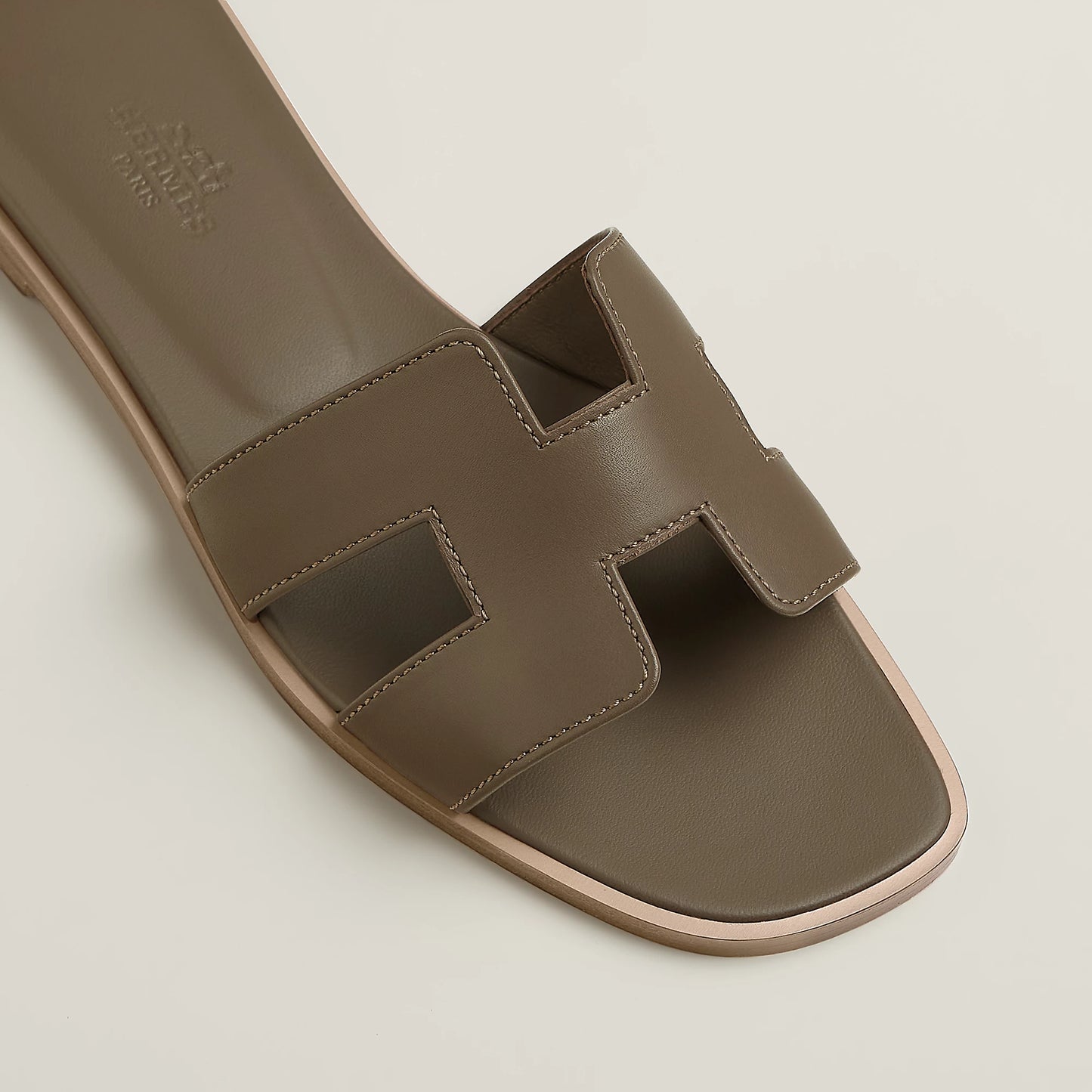 Taupe leather slide sandal close-up with stitched straps and open toe cutout