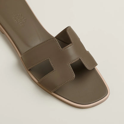 Taupe leather slide sandal close-up with stitched straps and open toe cutout