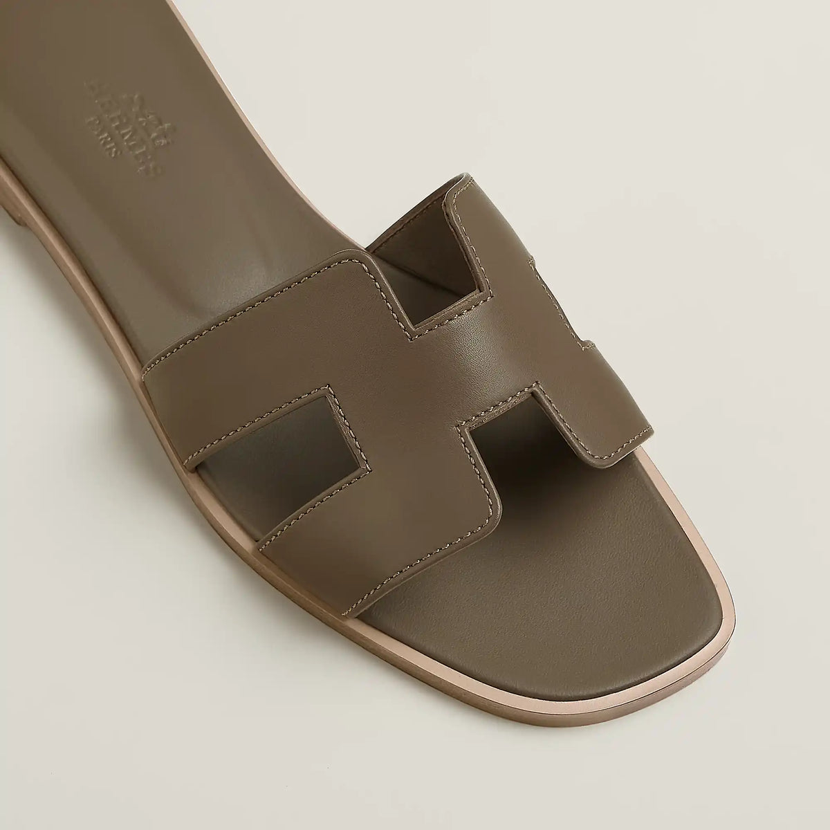 Taupe leather slide sandal close-up with stitched straps and open toe cutout