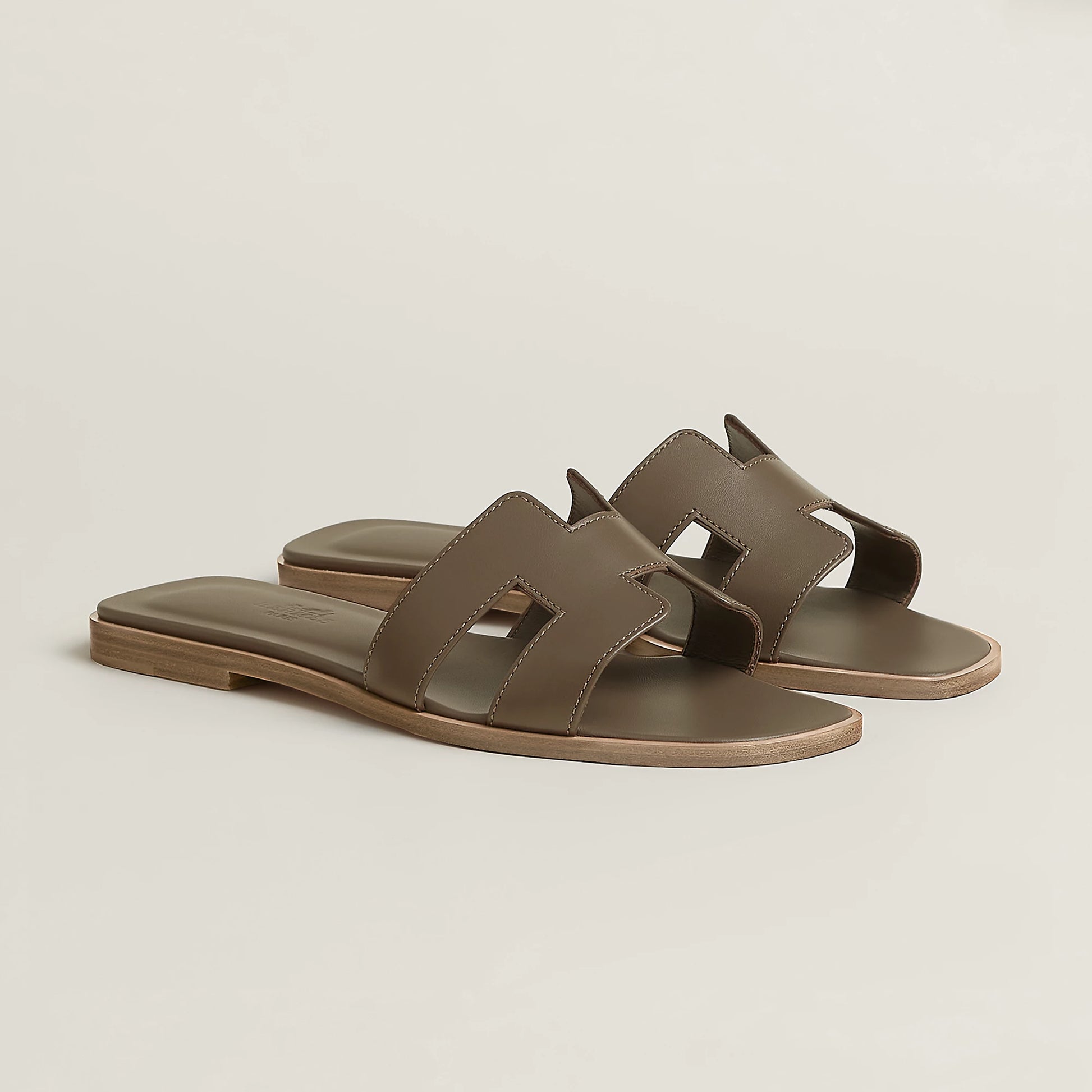 Taupe leather slide sandal with two wide straps and open toe, flat sole