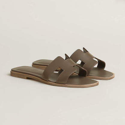 Taupe leather slide sandal with two wide straps and open toe, flat sole