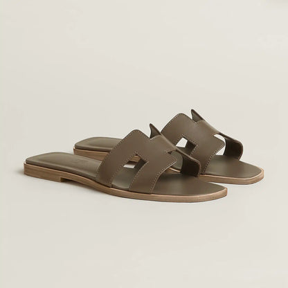Taupe leather slide sandal with two wide straps and open toe, flat sole