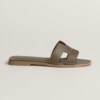 Beige leather slide sandal with two wide straps and open toe, flat sole