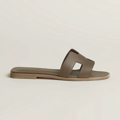 Beige leather slide sandal with two wide straps and open toe, flat sole