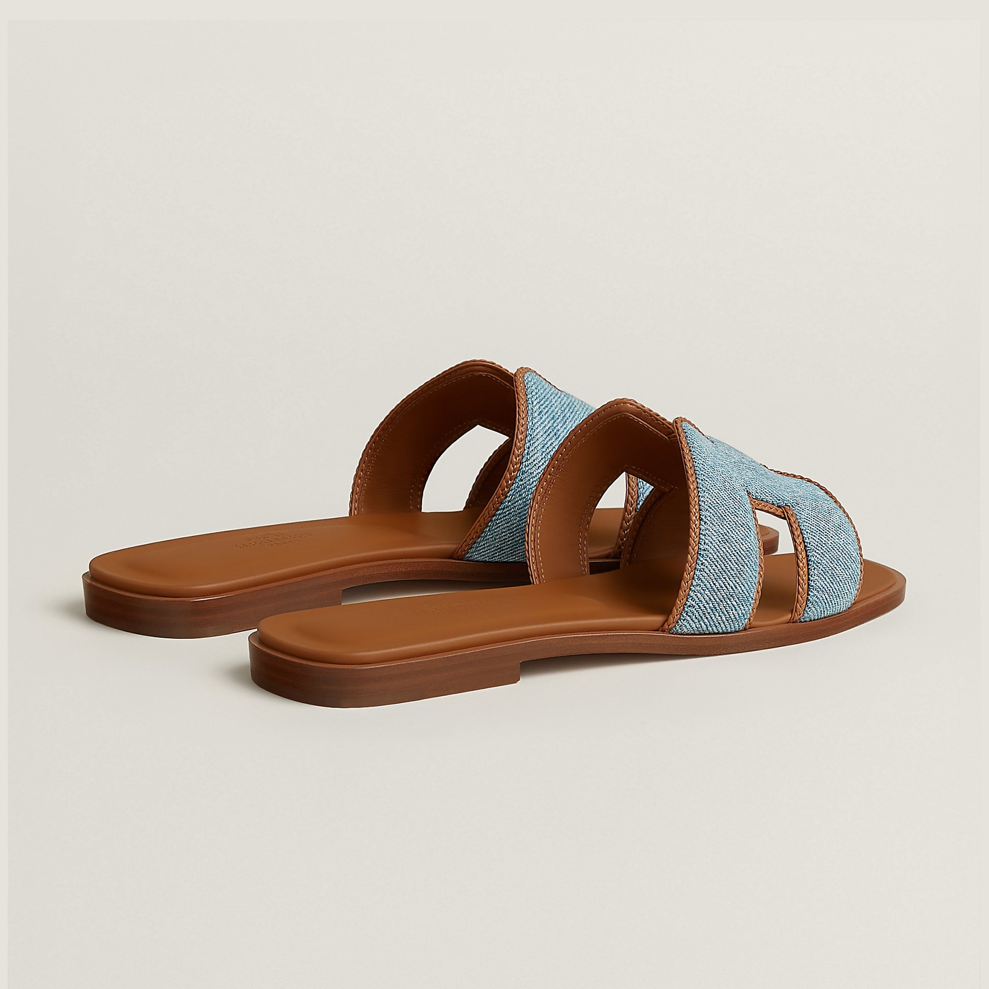 Hermès Oran slide sandal in light blue denim with tan leather straps and open toe