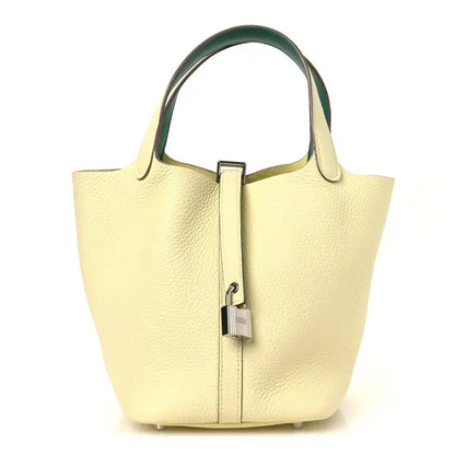 Two-tone leather handbag with yellow body, green top handles, and metal lock clasp.