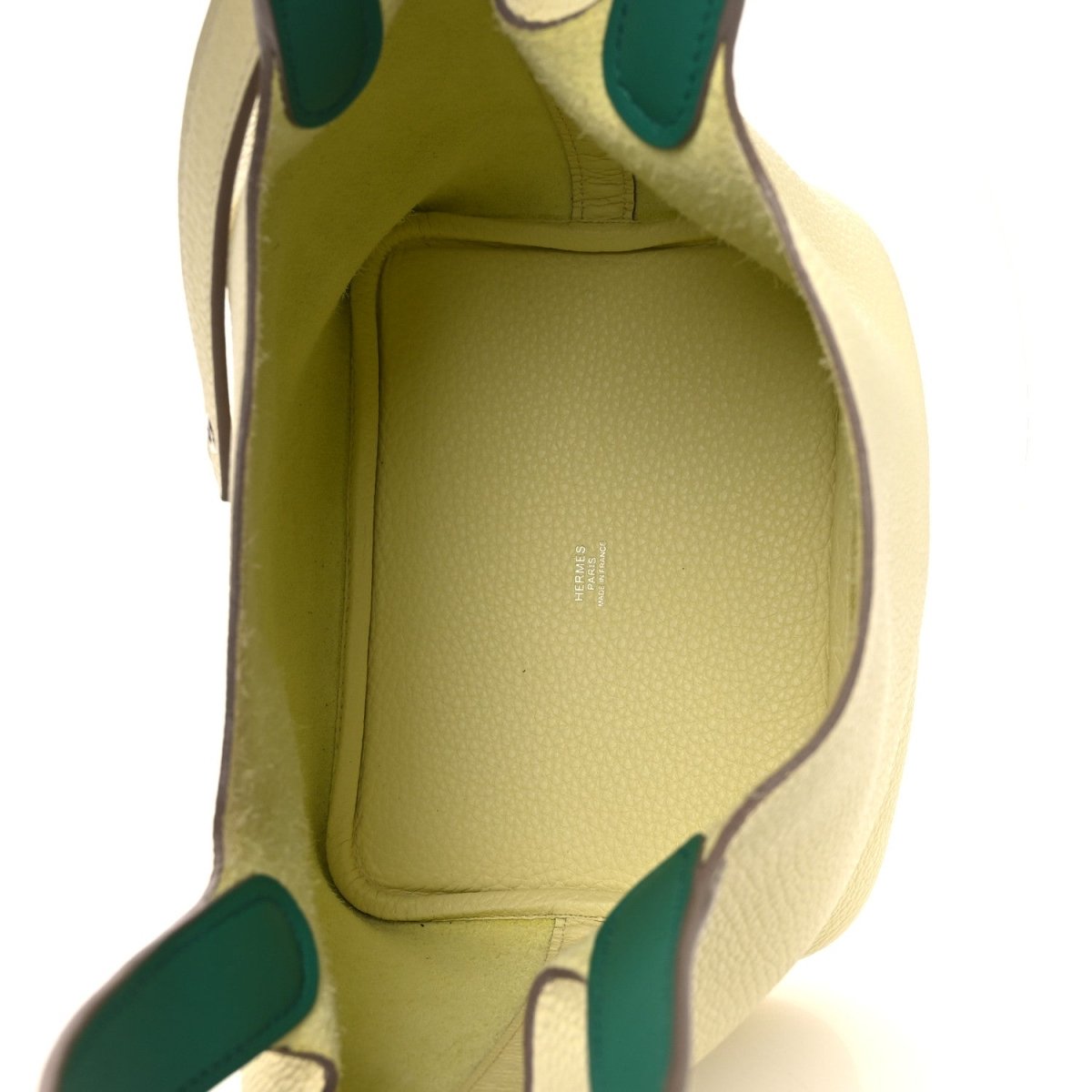 Two-tone leather handbag interior with yellow lining and green-trim edges.
