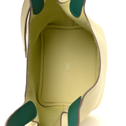 Two-tone leather handbag interior with yellow lining and green-trim edges.