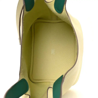 Two-tone leather handbag interior with yellow lining and green-trim edges.