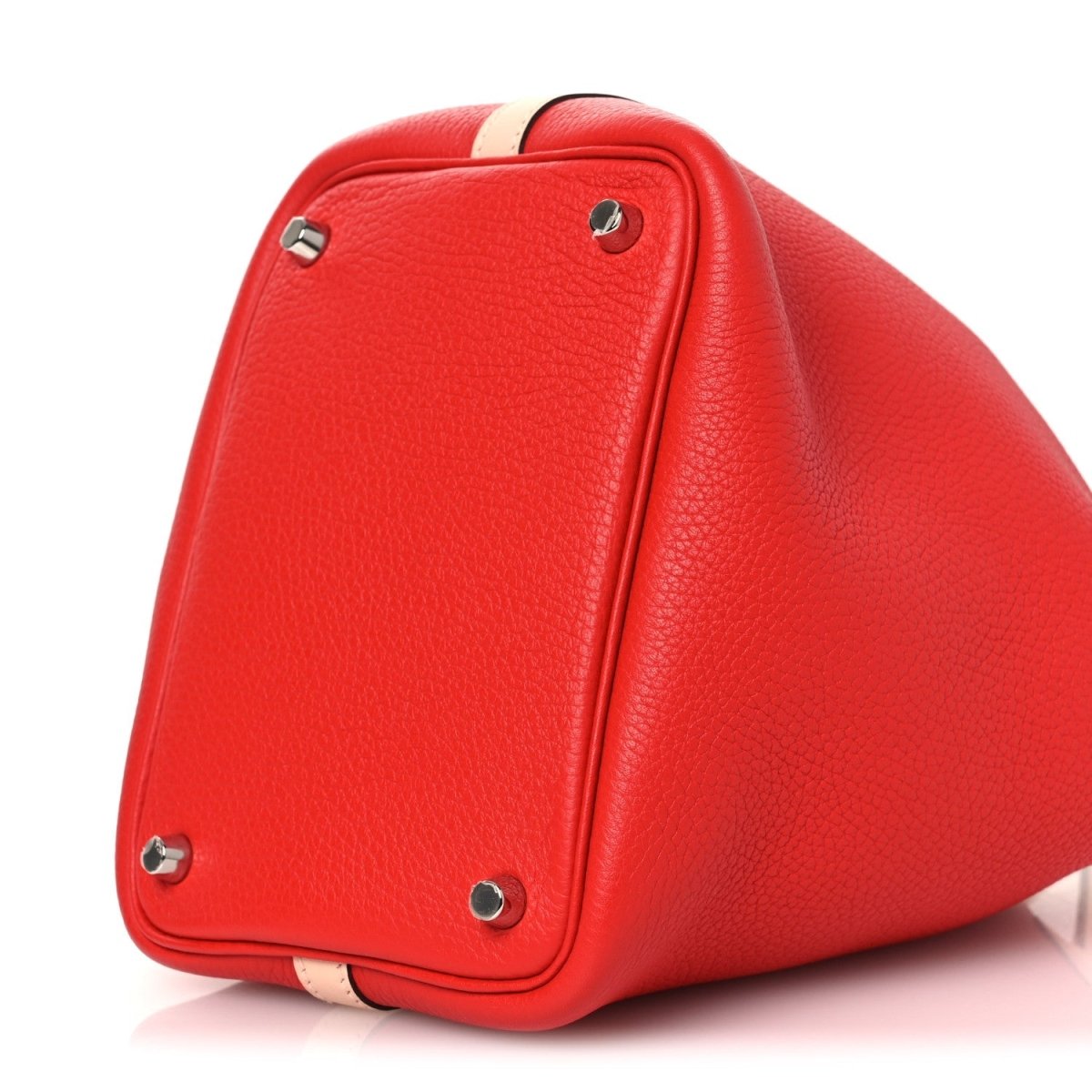 Red pebbled leather tote bag top view with silver rivets and pale handle accent.