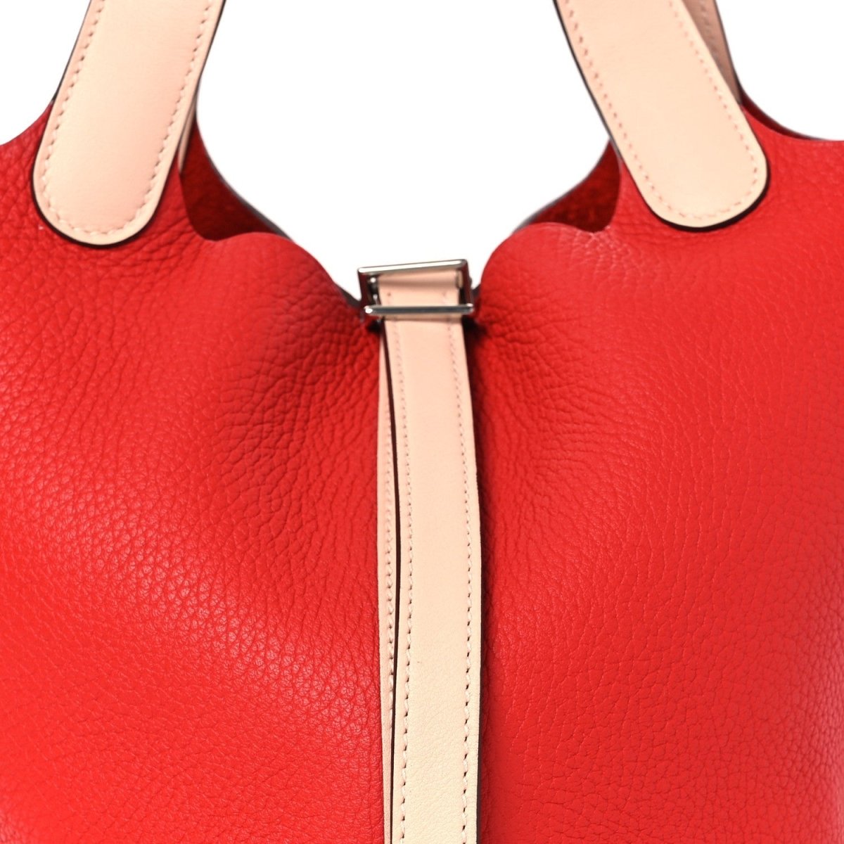 Close-up of red tote front lock clasp and pale handle straps.