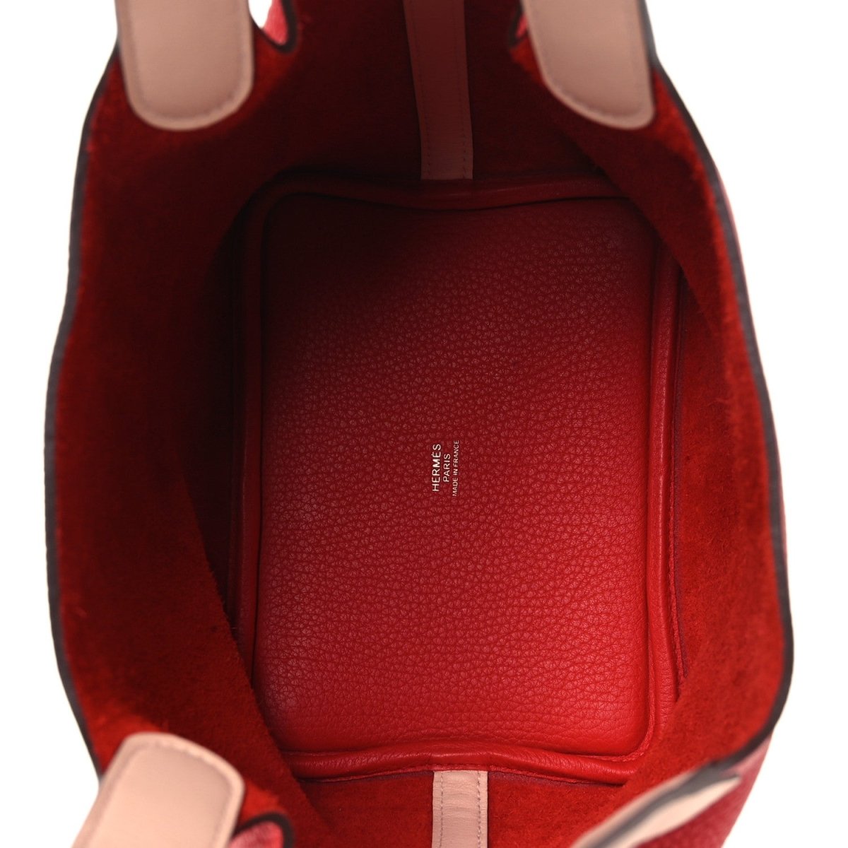 Red leather tote interior with side pocket and top opening; pale edge trim.
