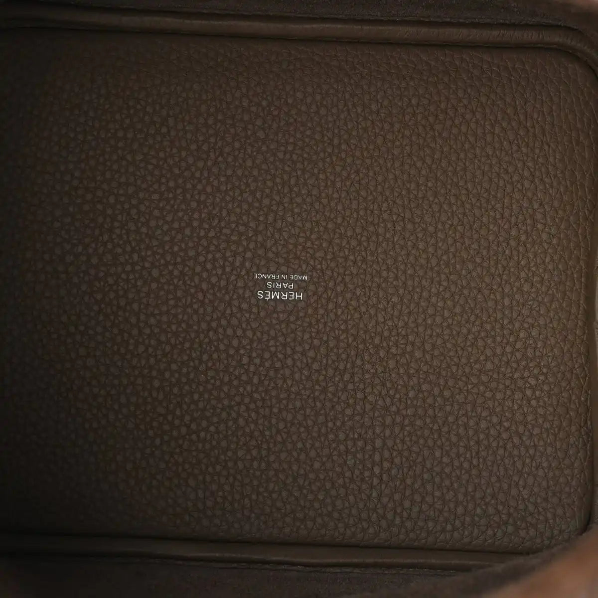 Taupe leather interior panel with embossed brand stamp on textured calfskin.