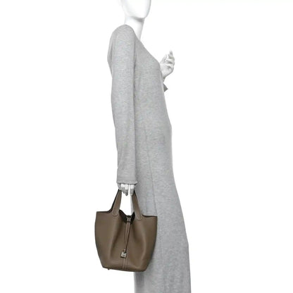 Taupe leather bucket bag with short handles and vertical zip-lock closure.