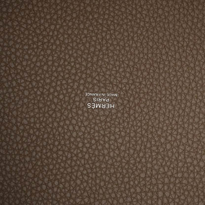 Taupe leather close-up with embossed “HERMES” stamp on textured calfskin.