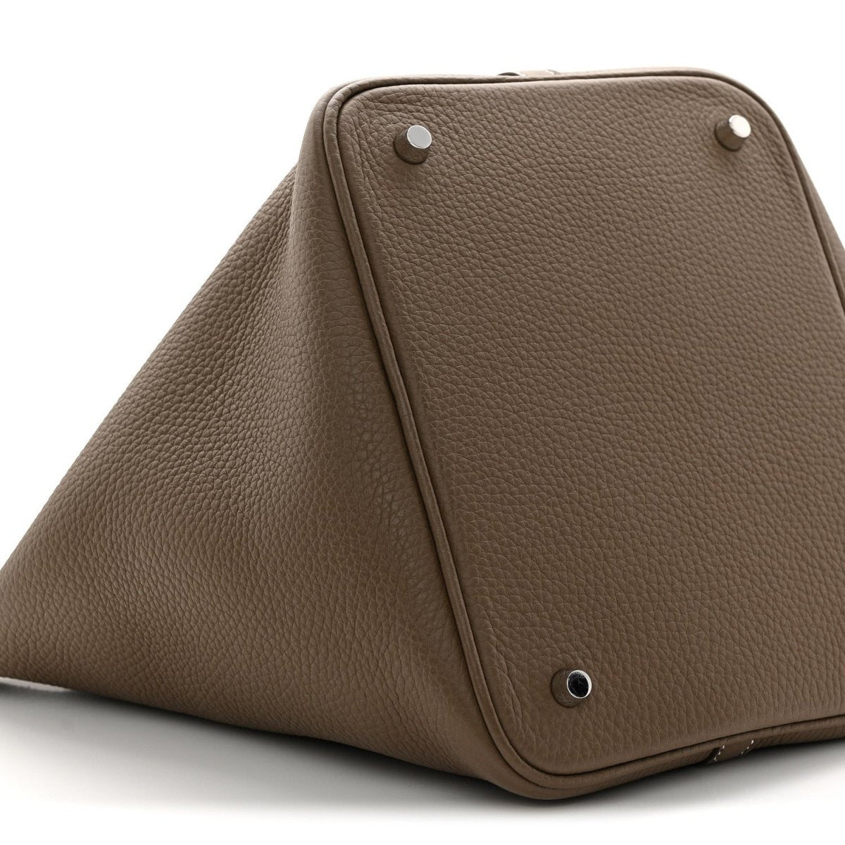 Taupe leather bucket bag top view with metal studs and triangular front frame.
