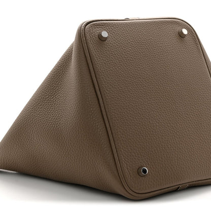Taupe leather bucket bag top view with metal studs and triangular front frame.