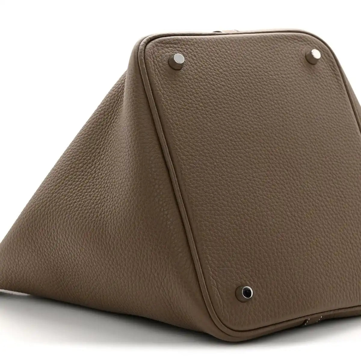 Taupe leather bucket bag top view with metal studs and triangular front frame.