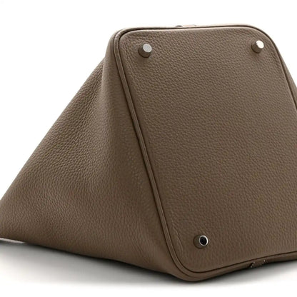 Taupe leather bucket bag top view with metal studs and triangular front frame.