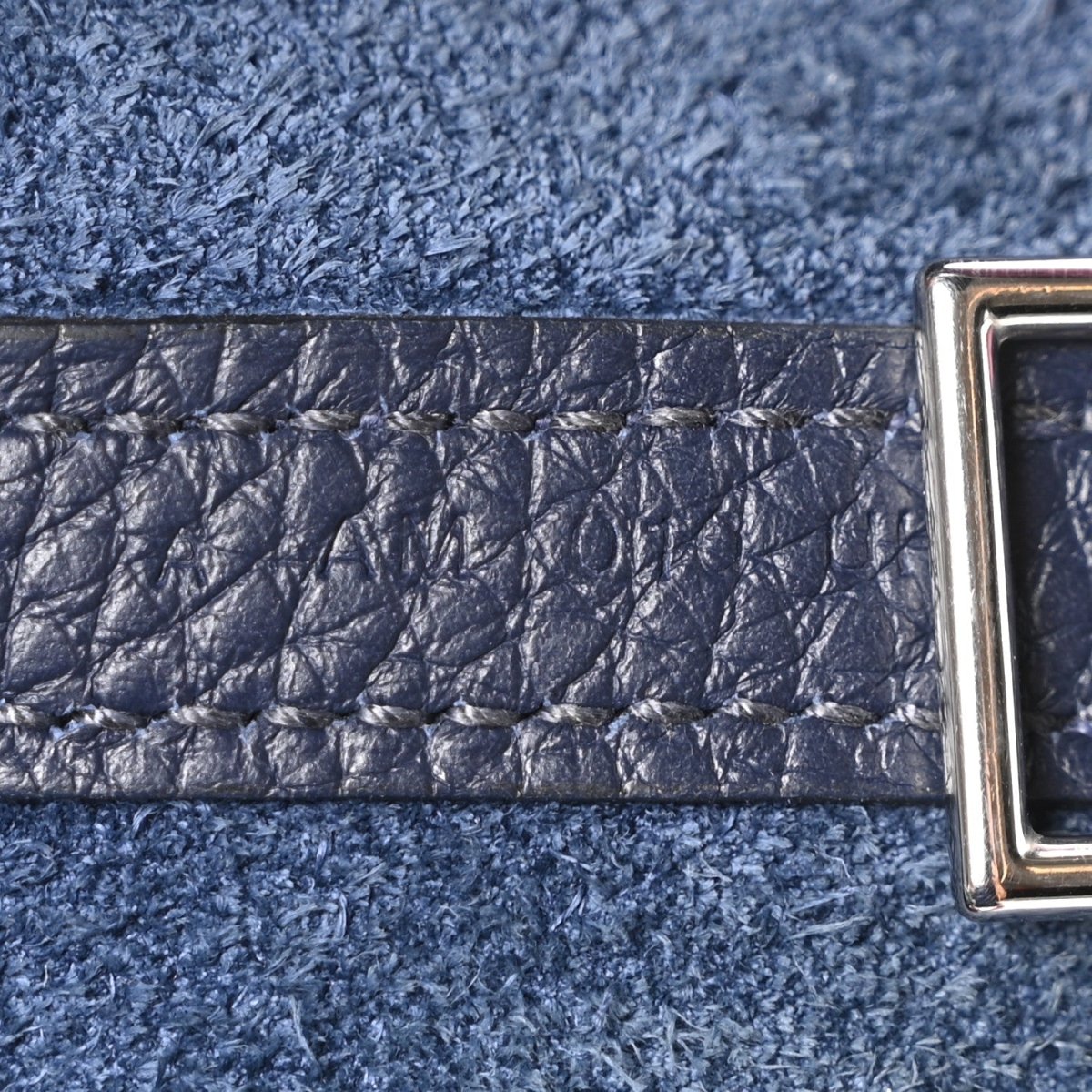 Navy leather bag strap close-up with metal clasp and textured finish