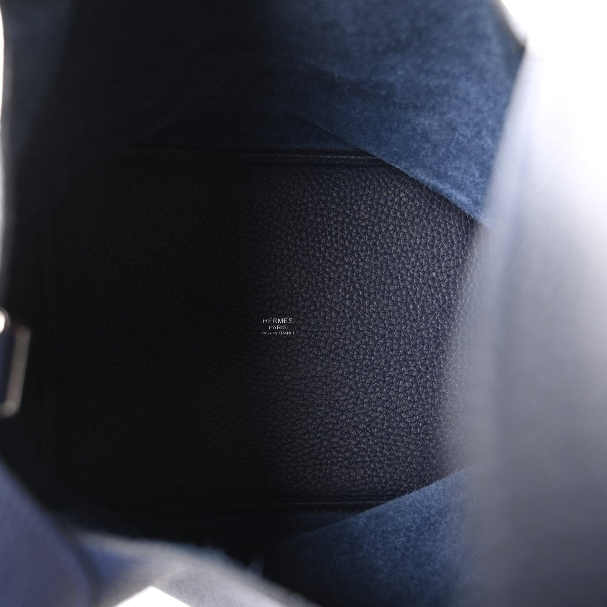 Navy leather bucket bag interior view with small stamped text on lining