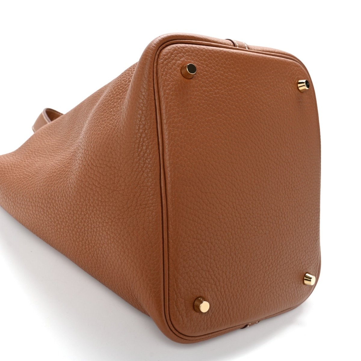 Brown leather tote bag with top flap, gold-tone corner accents, and rounded base.