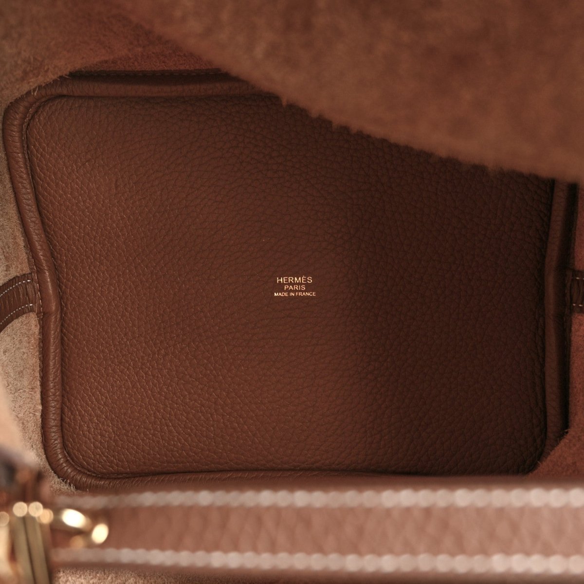 Leather interior of a brown tote bag with stitched trim and Hermes logo.