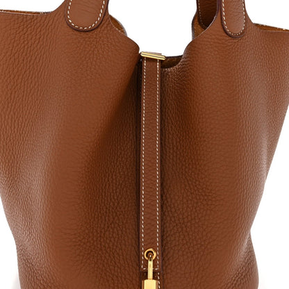 Close-up of brown leather tote with vertical lock zip and stitched edge trim.