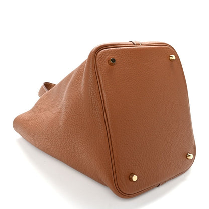 Brown leather handbag with top flap closure and gold-tone corner details.