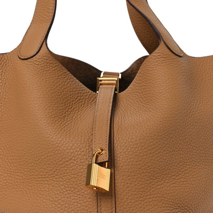 Leather tote zipper area with gold-tone lock hardware and tab