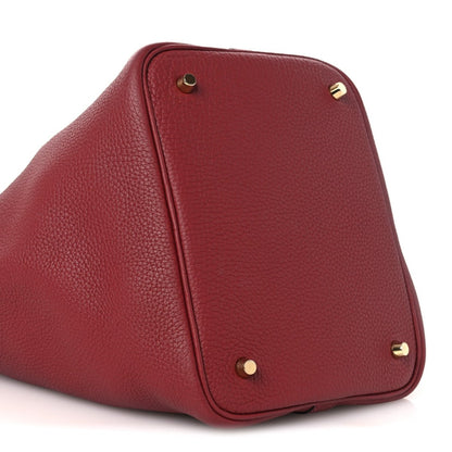Red leather tote bag end panel with gold feet and top seam detail.