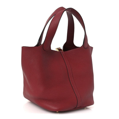 Red leather tote bag with wide handles, central seam, and gold-tone hardware.