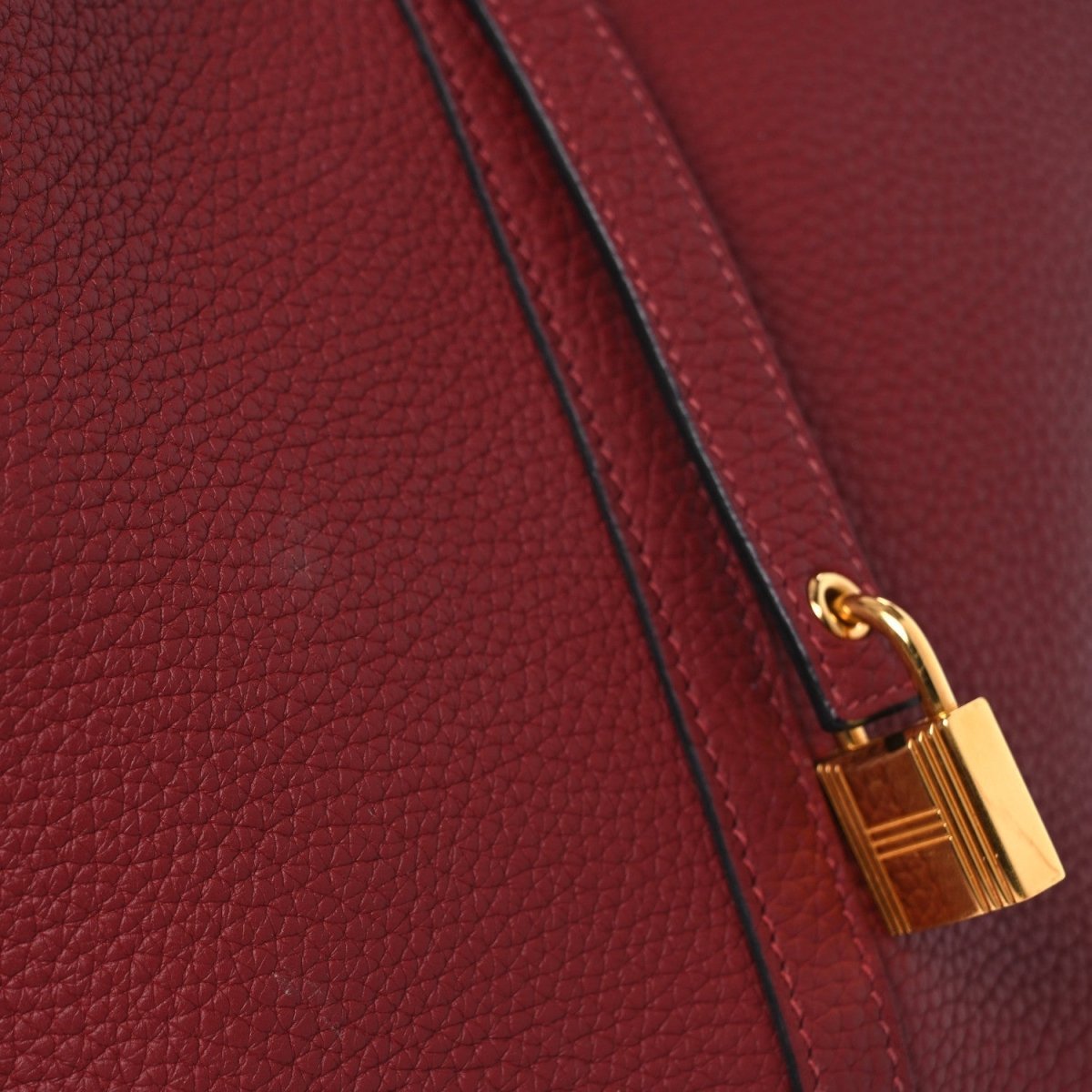 Red leather tote with gold padlock clasp and crossbody strap seam