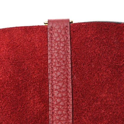 Red leather tote bag seam with adjustable strap and gold-tone clasp hardware.