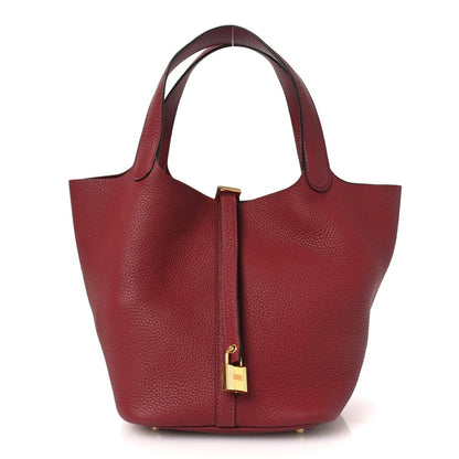 Red leather tote bag with top handles and center lock detail, gold hardware.