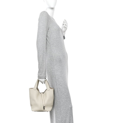 Off-white leather bucket bag carried by model with two top handles