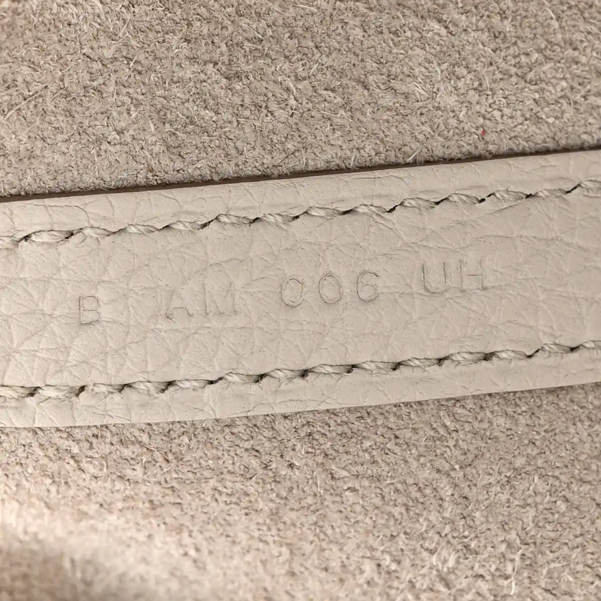 Off-white leather bucket bag seam with embossed maker marks and stitched edge