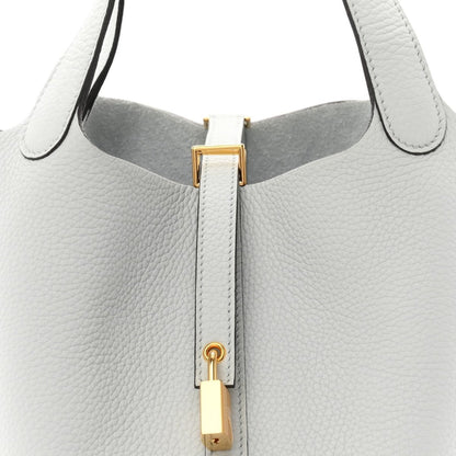 Light blue pebbled leather tote top with gold-toned lock hardware and zipper track