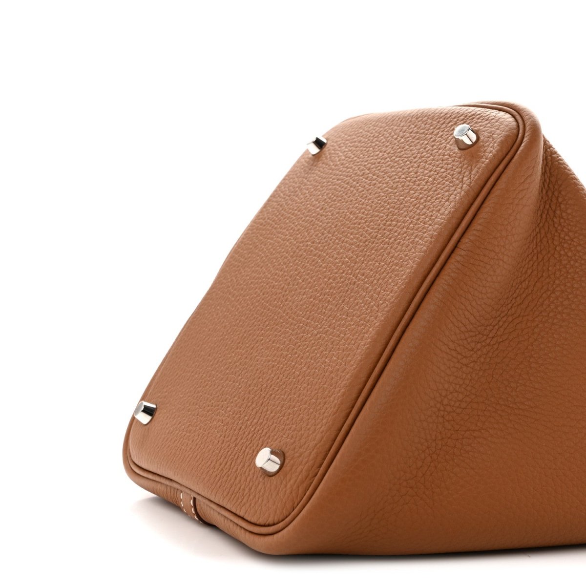 Tan leather tote bag top corner with metal feet and side seam
