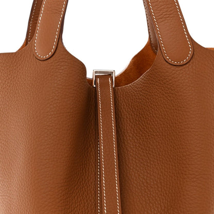 Tan leather tote bag lock clasp with silver metal hardware and stitched strap