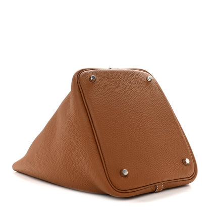 Tan leather tote bag with triangular fold and silver corner studs